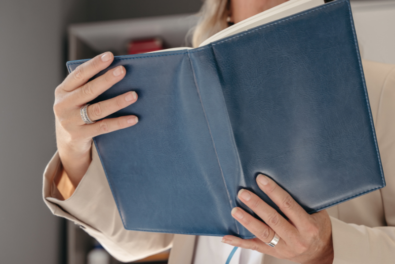 asesora fiscal de inages, sosteniendo libro corporativo de consulta en oficina.